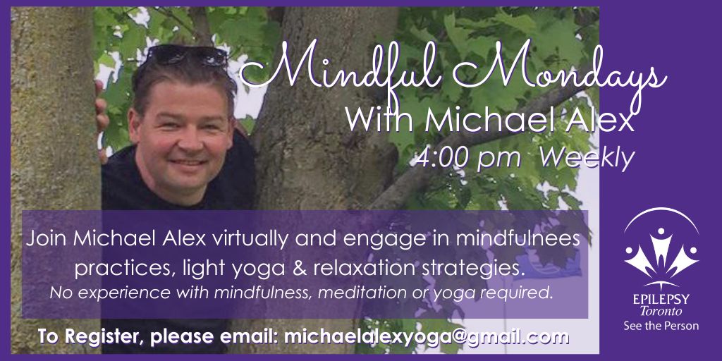 Michael Alex peers through a tree, smiling.