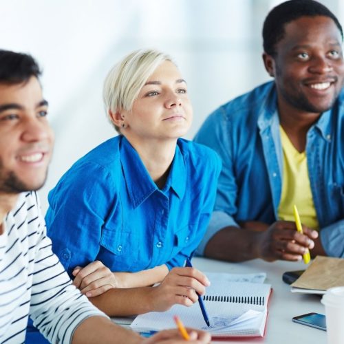3 people with notebooks in a classroom
