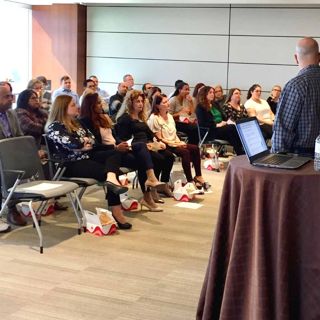 Epilepsy Presentation A man stands before a room of adults, sitting in chairs.
