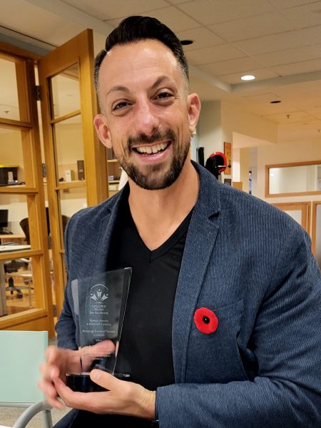 Evan Lewis HOPE Dr. Evan Lewis smiling and holding his H.O.P.E. award.